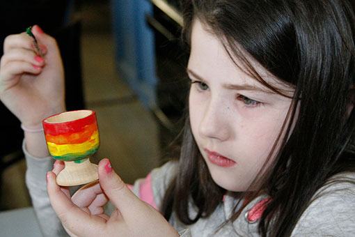 A child painting an egg cup